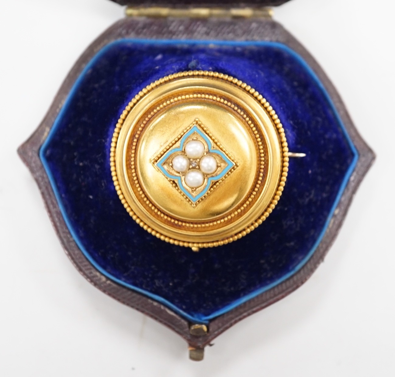 A cased Victorian yellow metal, enamel and split pearl set circular mourning pendant brooch, the glazed back with lock of hair beneath, diameter 34mm, gross weight 12.6 grams.